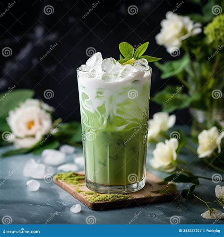 Closeup of an iced matcha latte in a glass with a stainless straw