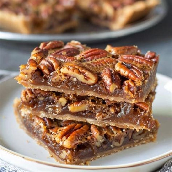 Three pieces of chocolate pecan pie bars stacked on top of each other.
